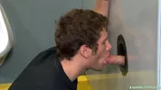 Un mec suce une bite à travers un gloryhole dans les vestiaires