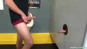 Un mec suce une bite à travers un gloryhole dans les vestiaires